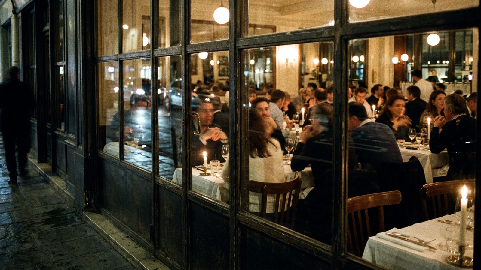 A full dining room seen at night from the pavement through a large window, the diners blurred by movement. Synthetic image.